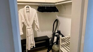 A walk-in closet with a robe hanging, a vacuum cleaner, and a shelf unit. - Sunset Studio Retreat (Los Angeles)