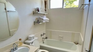 A bathroom with a toilet, sink, and bathtub, with a window above the bathtub. - Sunset Studio Retreat (Los Angeles)