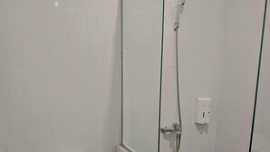 A bathroom with a toilet, a glass-enclosed shower, and tiled walls. - Hotel Pondok Asri Tawangmangu (Tawangmangu)