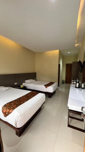 A hotel room with two beds, a desk, and a bathroom door. - Hotel Pondok Asri Tawangmangu (Tawangmangu)