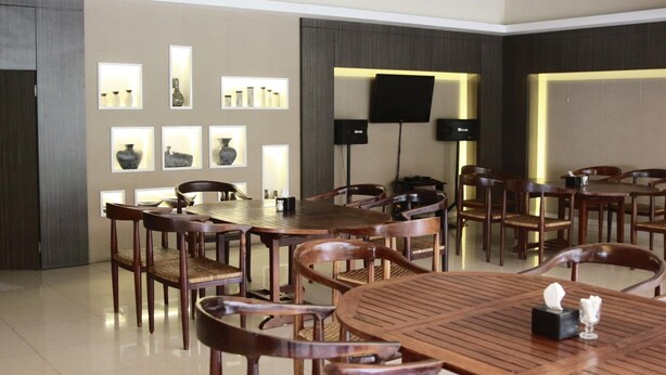 Zona pranzo con tavoli e sedie in legno, televisore a schermo piatto montato a parete e illuminazione a parete.