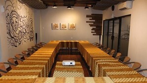 Une salle de conférence avec une longue table, des chaises, un projecteur et des œuvres d’art accrochées aux murs.