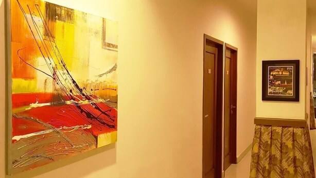 Un couloir avec un tableau, une porte et une photographie encadrée accrochée au mur.