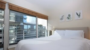 Een hotelkamer met een groot bed, een raam met zonwering en drie kunstwerken aan de muur.