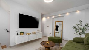 A modern living room with a flat-screen TV, a green sofa, a round coffee table, and a white cabinet. - Holiday home with Wi-Fi and air conditioning (Funtana)