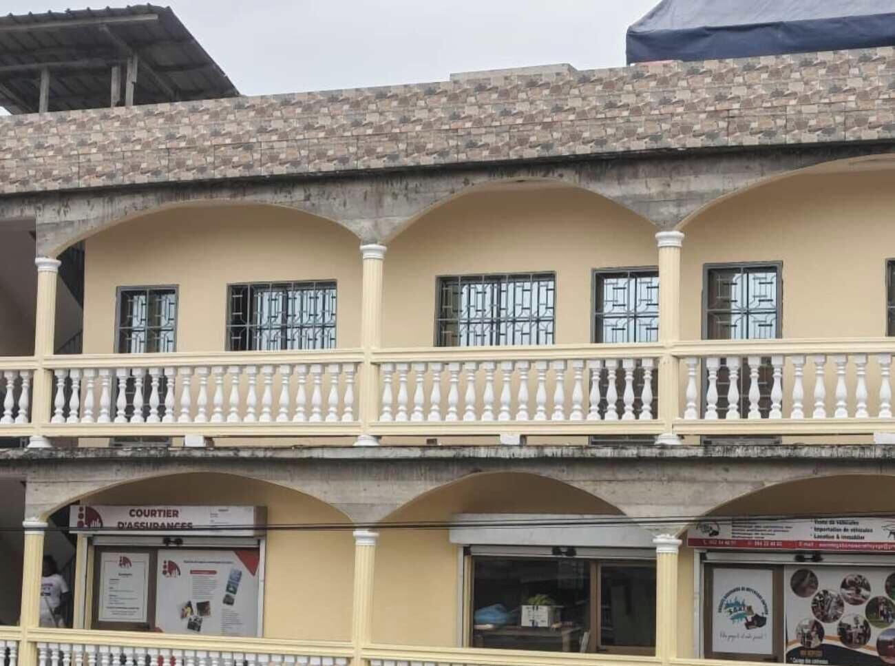 Un edificio de varios pisos con un balcón, una tienda con un letrero y un escaparate con un cartel.