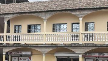 Un edificio de varios pisos con un balcón, una tienda con un letrero y un escaparate con un cartel.