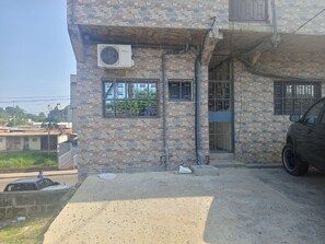 A building with stone walls, a Westpool air conditioning unit, a gated entrance, and a parked car.