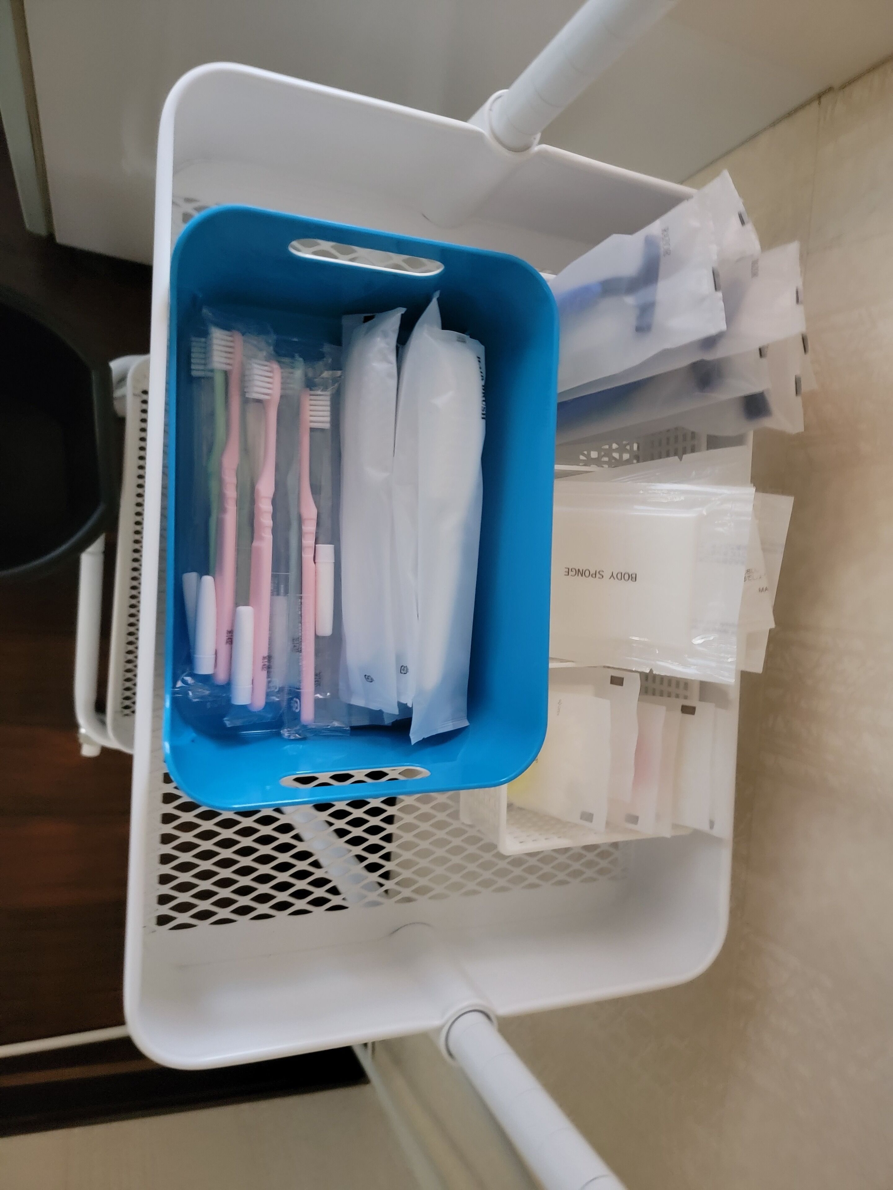A blue basket containing toothbrushes and dental floss, placed on a white tray.