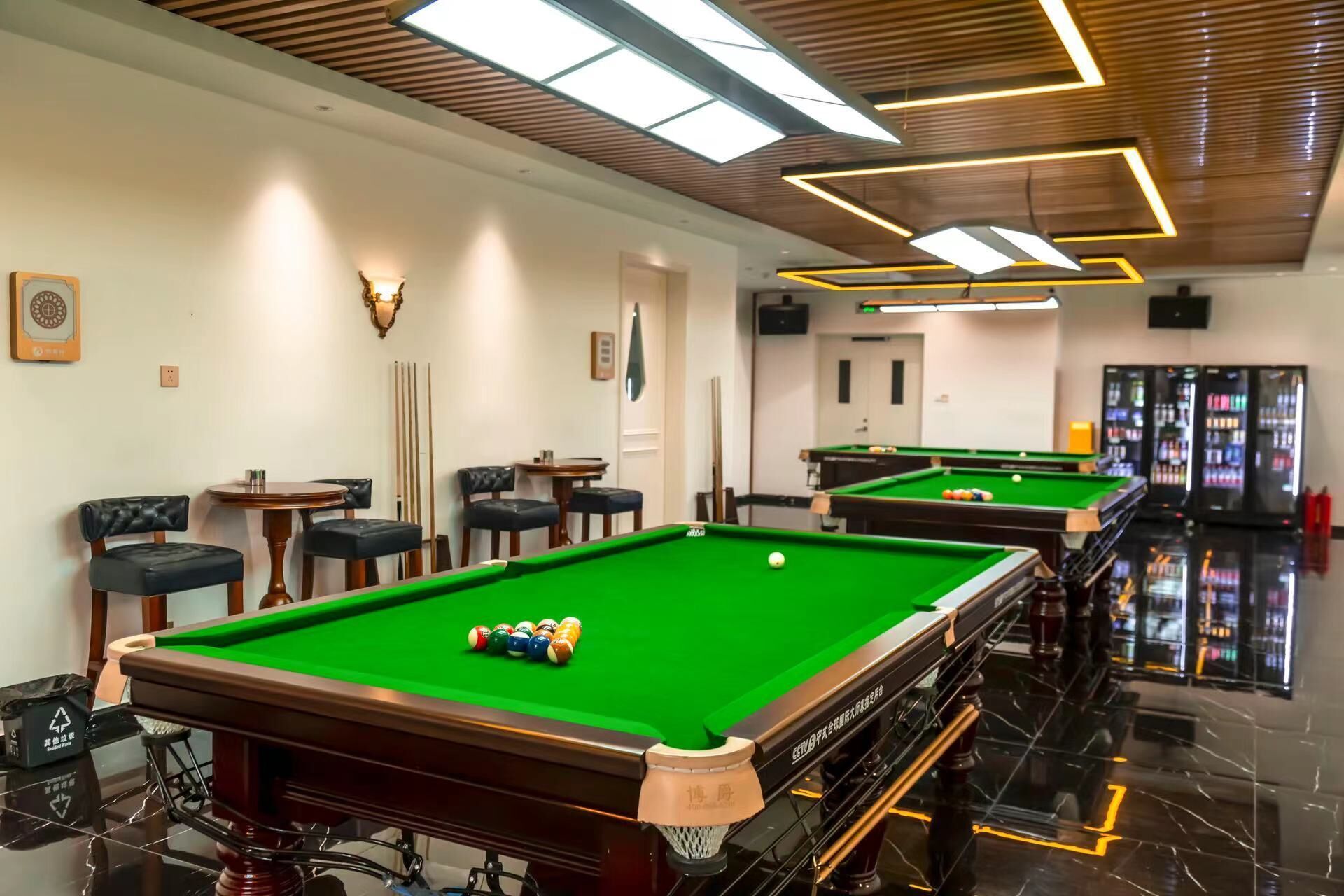 A pool hall with multiple tables and a billiards ball rack.