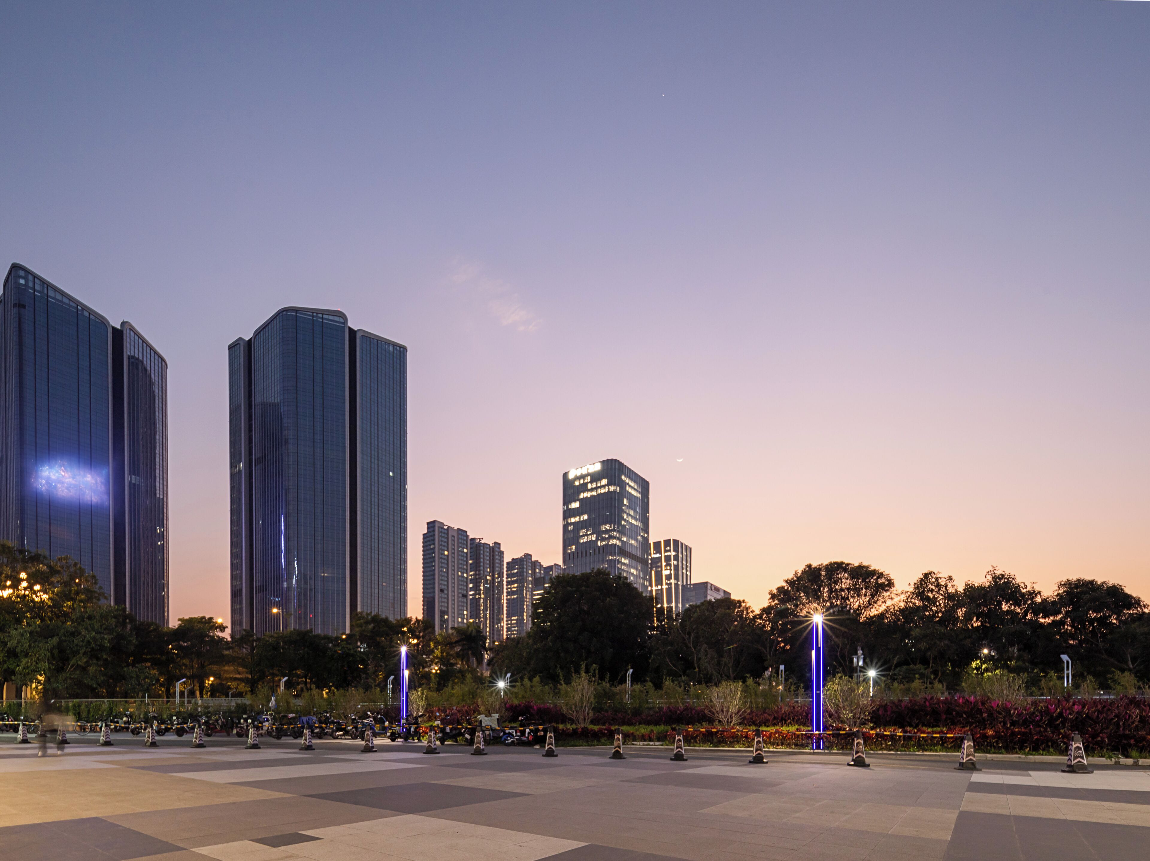 A cityscape with modern skyscrapers and a plaza with geometric paving.
