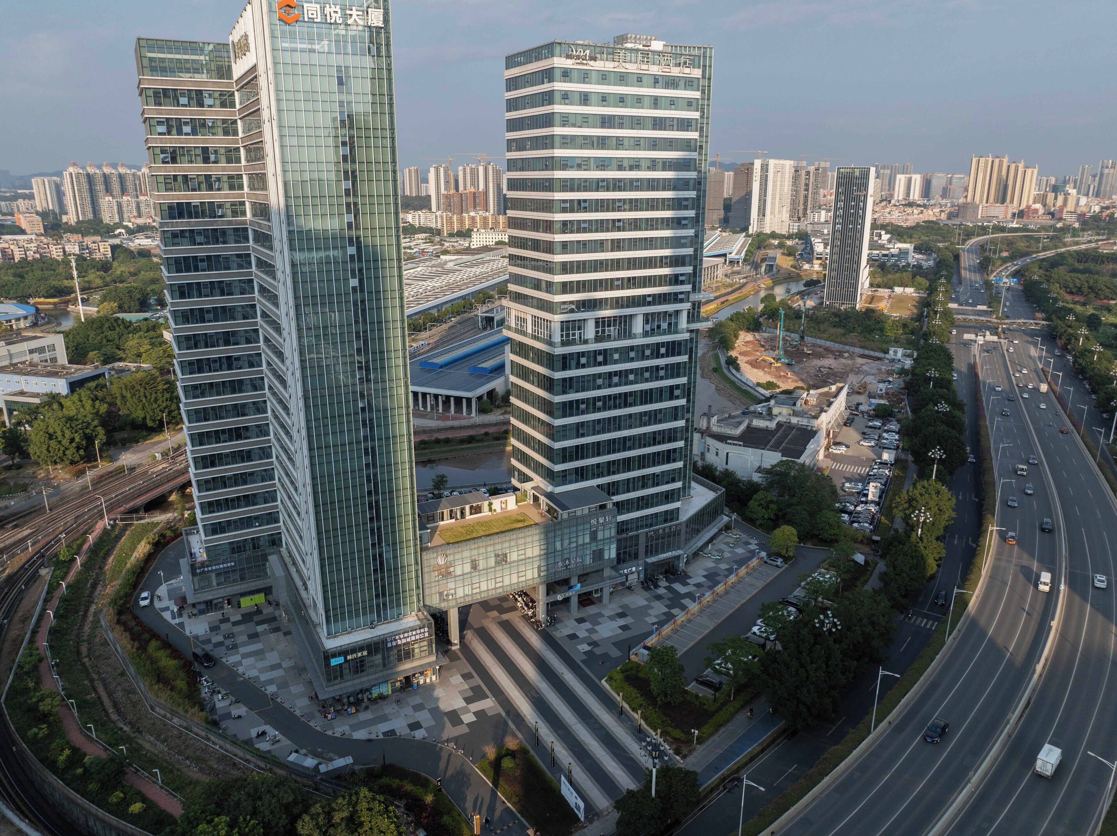 A high-rise building with a glass facade, surrounded by a busy urban environment with roads and other buildings.