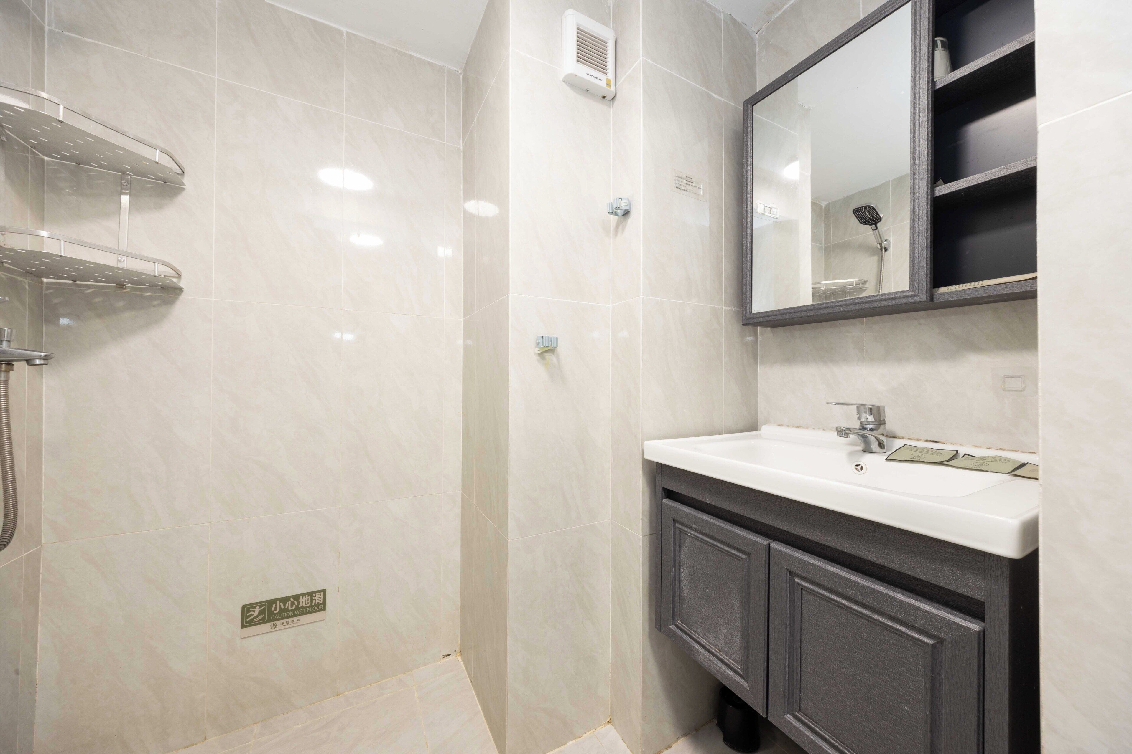A bathroom with a shower, a sink, a mirror, and a cabinet.