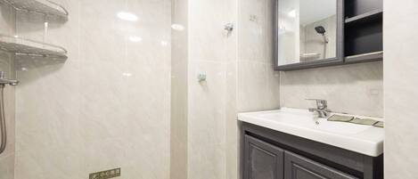 A bathroom with a shower, a sink, a mirror, and a cabinet.