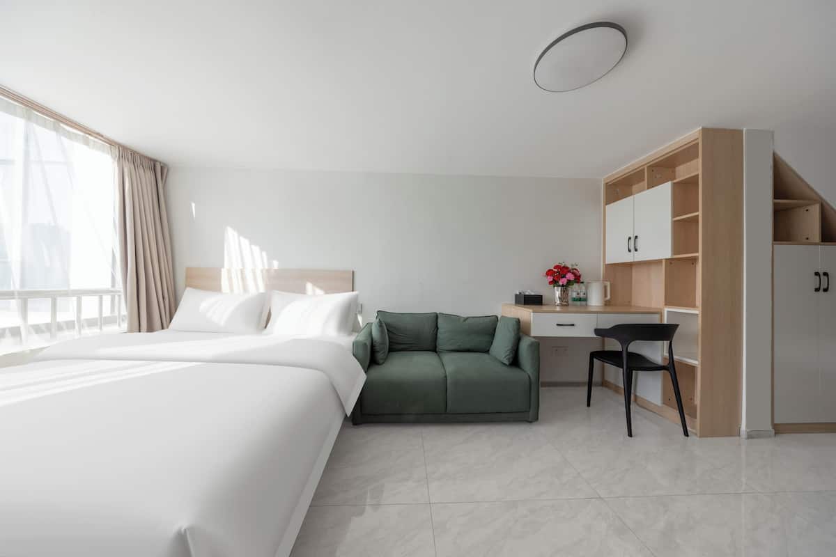 Una habitación de hotel moderna con una cama, un sofá verde, un escritorio y un armario.