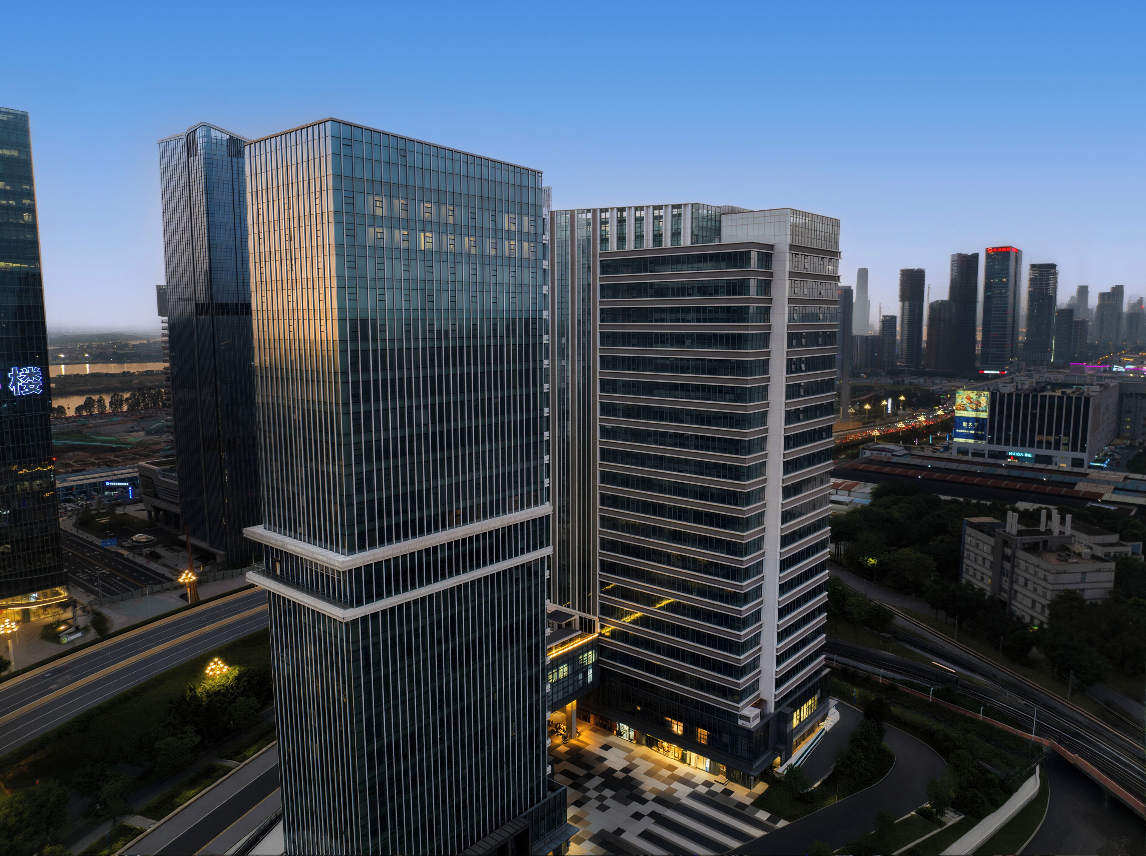 A modern high-rise building with a glass facade, surrounded by other skyscrapers and a busy urban environment.