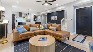 A modern living room with a sectional sofa, a round coffee table, and a ceiling fan. - NEW Spacious and fun packed large home in Baltimore County (Reisterstown)