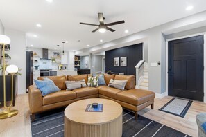 A modern living room with a sectional sofa, a round coffee table, and a ceiling fan. - NEW Spacious and fun packed large home in Baltimore County (Reisterstown)