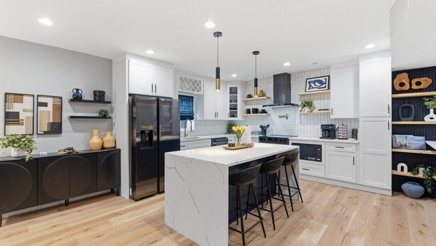 A modern kitchen with a central island, bar stools, and a refrigerator. - NEW Spacious and fun packed large home in Baltimore County (Reisterstown)