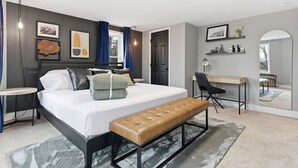 A modern bedroom with a bed, bench, desk, and chair, featuring artwork and a mirror. - NEW Spacious and fun packed large home in Baltimore County (Reisterstown)