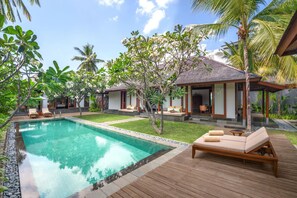 A pool with lounge chairs, a wooden deck, and a tropical garden. - The Sira, a Luxury Collection Resort & Spa, Lombok (Tanjung)