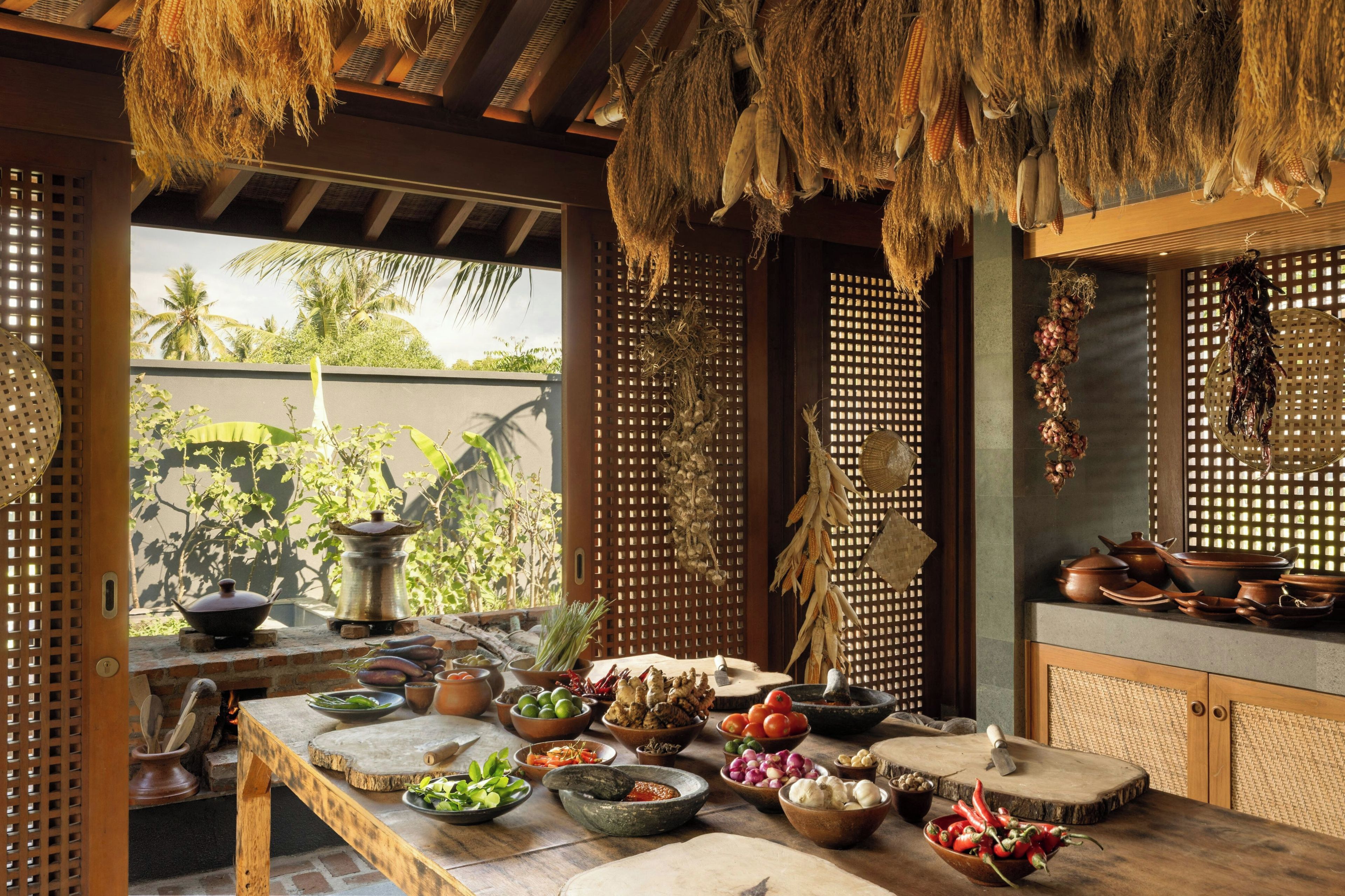 A traditional kitchen with a wooden table, various cooking utensils, and hanging dried corn.