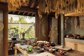 A traditional kitchen with a wooden table, various cooking utensils, and hanging dried corn. - The Sira, a Luxury Collection Resort & Spa, Lombok (Tanjung)