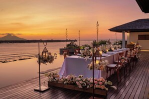 A sunset view with a dining area on a wooden deck overlooking a body of water. - The Sira, a Luxury Collection Resort & Spa, Lombok (Tanjung)