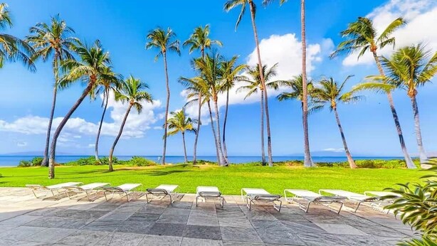 A resort with a pool area, palm trees, and a view of the ocean. - Kihei Beach Stay at Hale Kai O' Kihei - Oceanfront in Maui (Kihei)