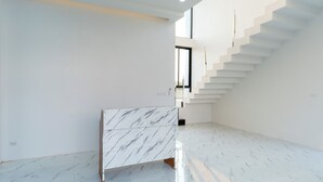 A modern interior with a marble counter, a staircase, and a large window. - Deluxe Hotel Chaiyaphum (Chatturat)