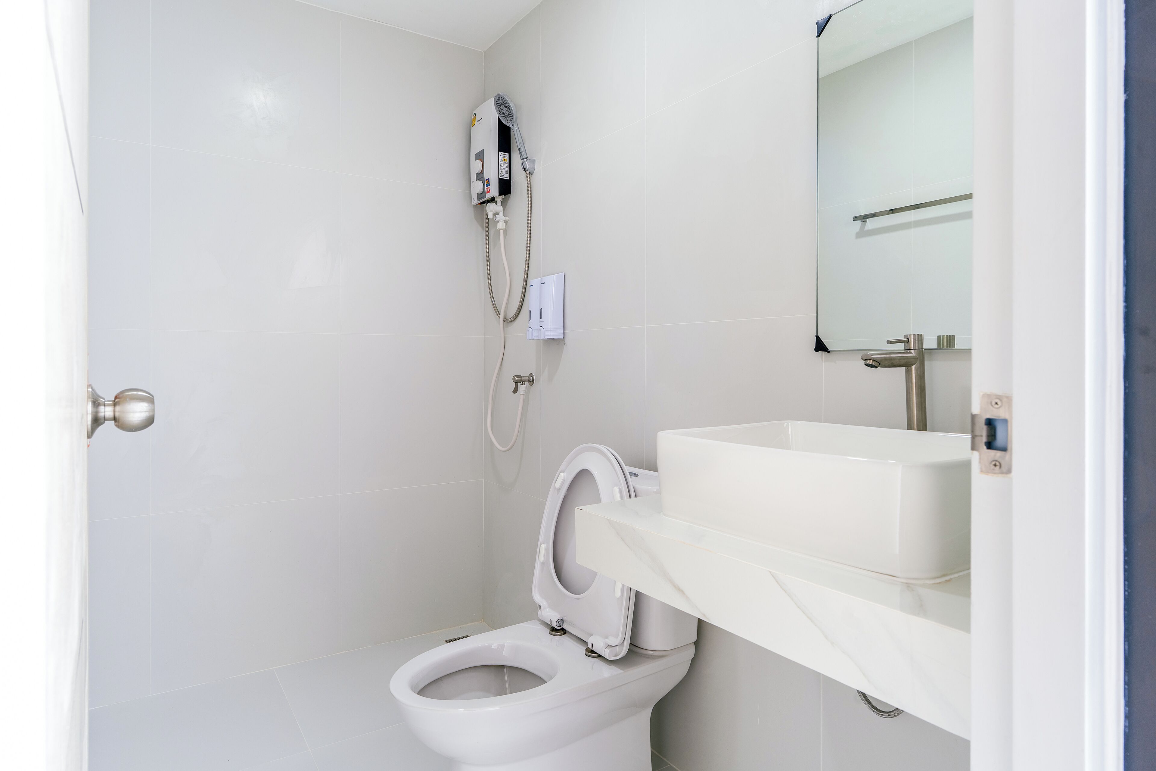 A bathroom with a toilet, a shower, and a sink.