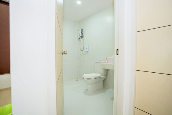 A bathroom with a toilet, a shower, and a sink.