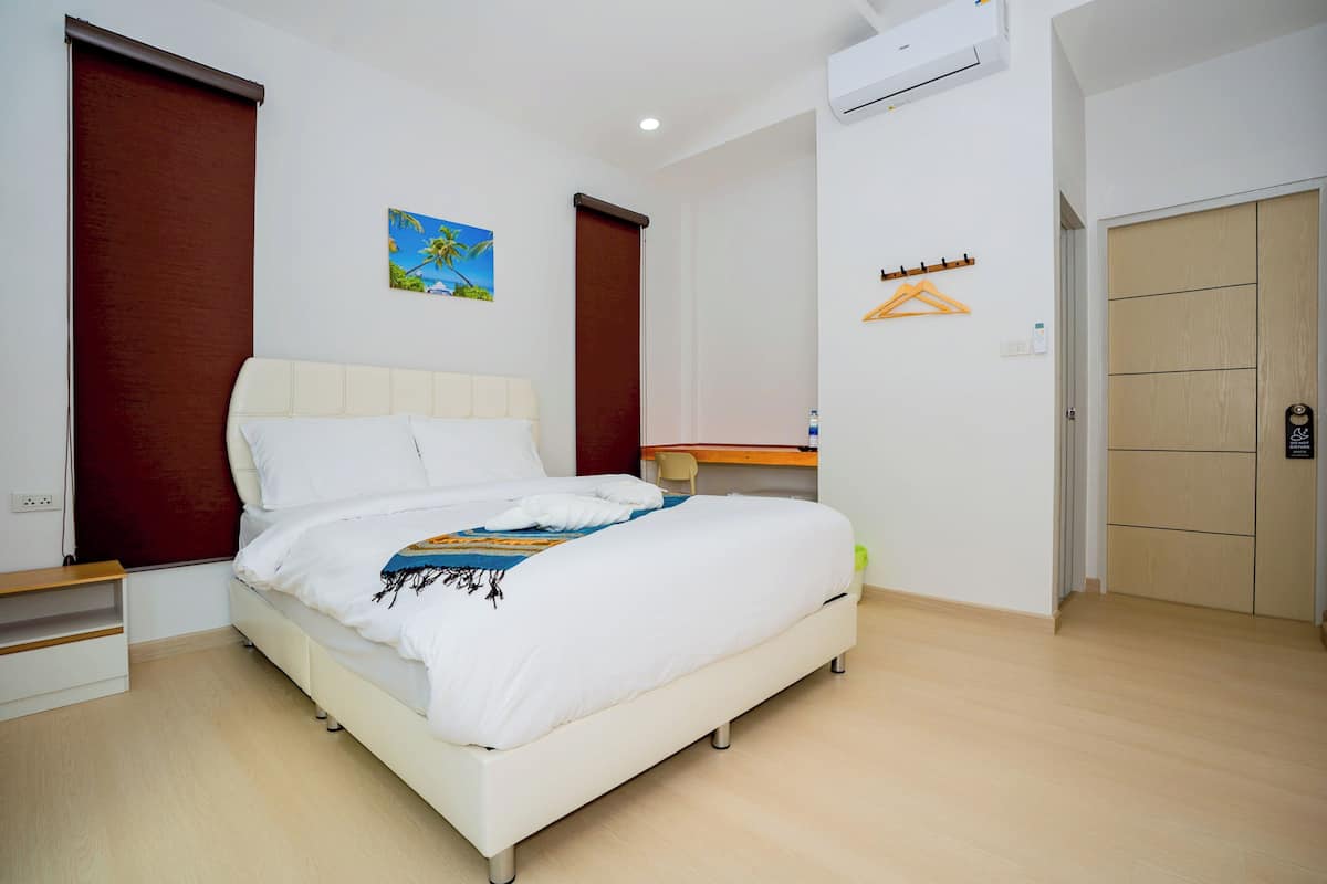 A bedroom with a bed, a desk, and a wardrobe.