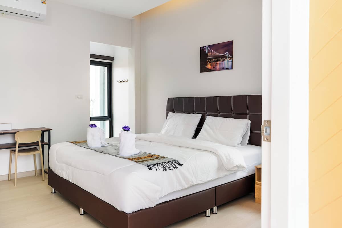 A modern hotel room with a bed, a desk, a chair, and a window.