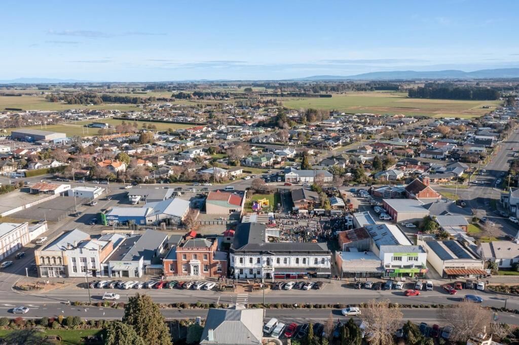 En by med en blanding af bolig- og erhvervsbygninger, en central vej og en parkeringsplads.
