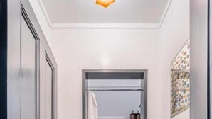 A narrow hallway with a door leading to a bathroom, a trash bin, and a towel rack. - Railway Hotel Winton (Winton)