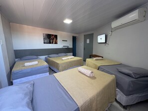 A hotel room with four beds, a mounted TV, and an air conditioning unit. - Pousada O leão (Piaçabuçu)