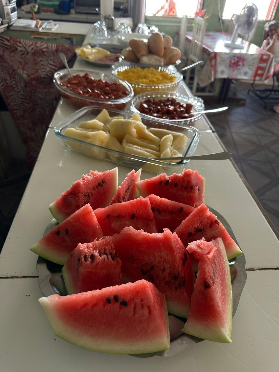 A buffet table with various food items including watermelon slices, bananas, and other fruits.