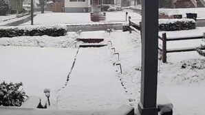 Un porche cubierto con vistas a una casa y jardín nevados.