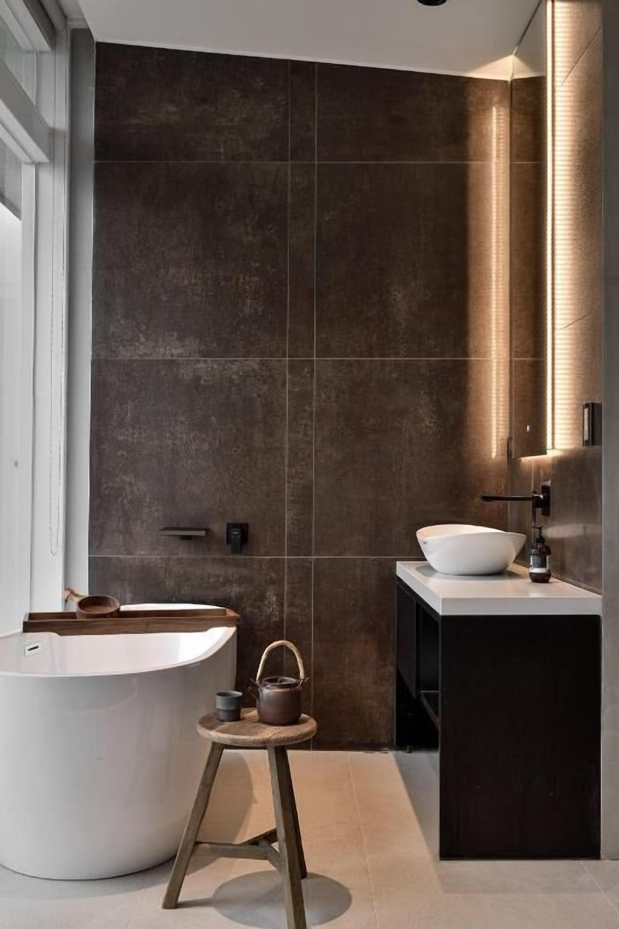 Une salle de bain moderne avec une baignoire sur pieds, un petit tabouret avec une bouilloire et un grand miroir.