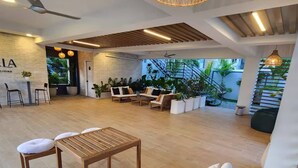 A spacious living area with a sofa, a table, and chairs, a staircase, and a reception desk.