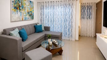 A modern living room with a sectional sofa, a glass coffee table, and a flat-screen TV.