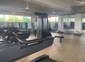 Ein Fitnessstudio mit Cardiogeräten, Krafttrainingsmaschinen und Bänken.