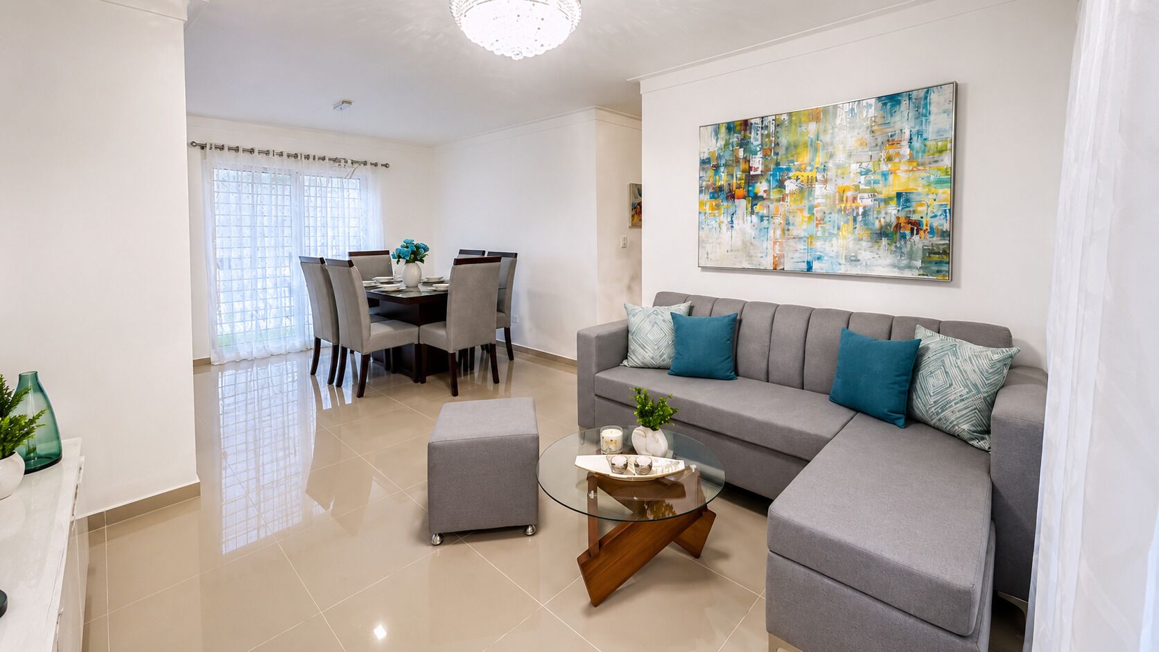 Una sala de estar moderna con un sofá gris, una mesa de centro de vidrio y un comedor con una mesa y sillas.