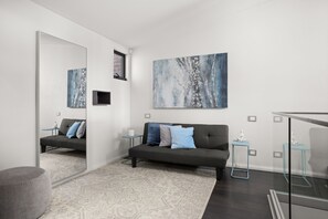Ein modernes Wohnzimmer mit einem grauen Sofa, einem gemusterten Teppich und einem großen, abstrakten Gemälde an der Wand.
