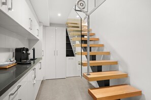 Eine moderne Küche mit einer Holztreppe, die in einen Essbereich führt.