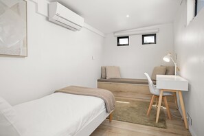 Ein schlicht eingerichtetes Zimmer mit einem Bett, einem Schreibtisch und einem Fenster.