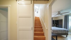 A staircase leading to a bedroom with a bed, a ceiling fan, and a view of the outdoors.