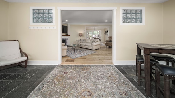 A living room with a sofa, a coffee table, and a rug. There is a dining area with a table and chairs.