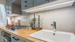 Una cocina moderna con estufa de acero inoxidable, un lavamanos blanco y armarios grises.